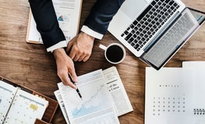 business man in suit at desk with papers and laptop